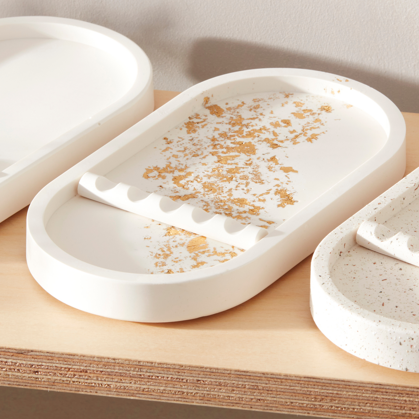 Set of white ceramic trays with gold speckles on a wooden surface